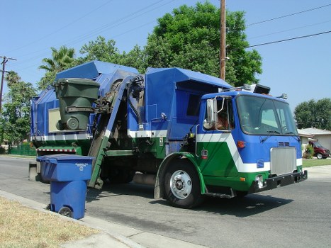 Company vehicle parked with skip being loaded, safety cones visible